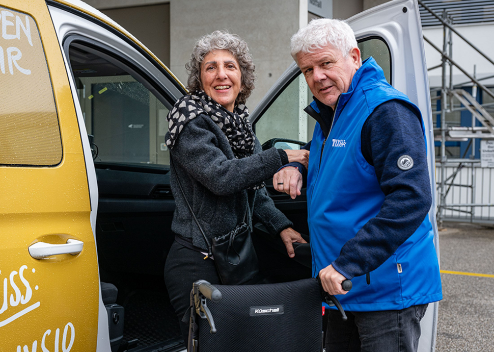 Fahrer Marco Maeder hilft Bernadette Andreoli beim Einsteigen ins Auto.
