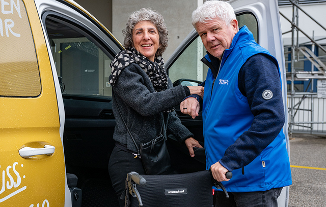 Fahrer Marco Maeder hilft Bernadette Andreoli beim Einsteigen ins Auto.